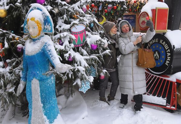 Девушки фотографируются на фоне новогодней елки у ГУМа в Москве во время снегопада - Sputnik Латвия