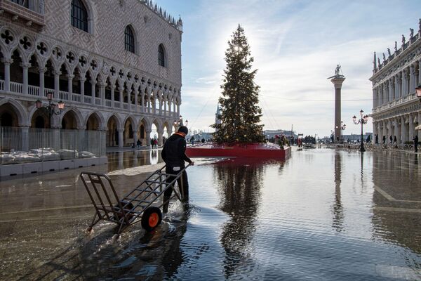 Носильщик пробирается через площадь Сан-Марко, затопленную морским приливом в Венеции, Италия. - Sputnik Латвия