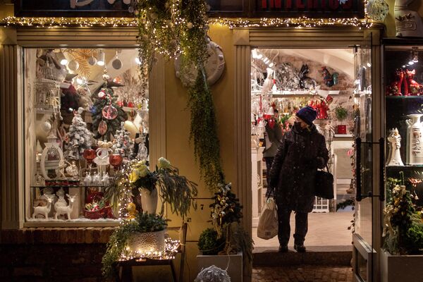 Женщина в маске смотрит на рождественские украшения в магазине в Вильнюсе, Литва. - Sputnik Латвия