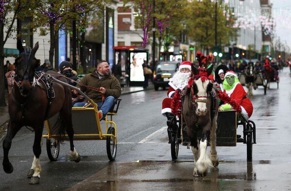 Люди в рождественских нарядах едут в запряженной лошадьми повозке в Лондоне, Великобритания. - Sputnik Латвия