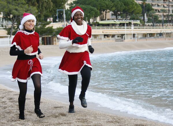 Девушки в костюмах Санта-Клауса совершают пробежку перед зимним купанием в Средиземном море. - Sputnik Латвия