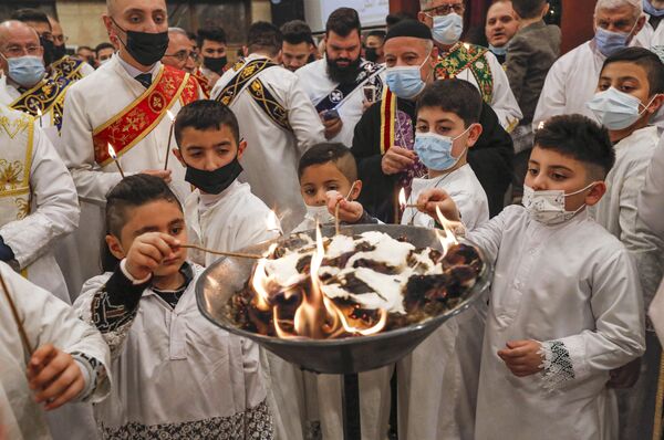 Юные алтарники зажигают свои свечи во время Рождественской мессы в сирийской православной церкви Ум аль-Нур в Эрбиле, столице автономного курдского региона на севере Ирака. - Sputnik Латвия