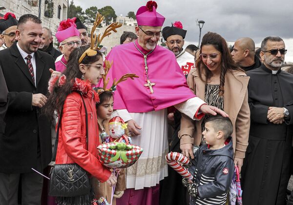 Пьербаттиста Пиццабалла (в центре), латинский патриарх Иерусалима, приветствует детей, прибывающих в церковь Рождества во время рождественских праздников в городе Вифлеем. - Sputnik Латвия