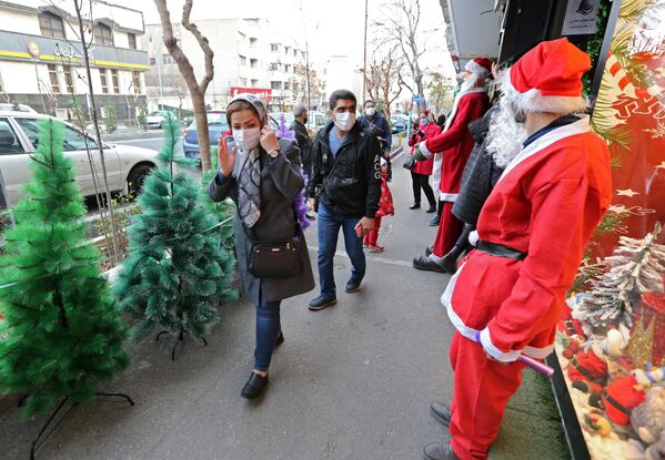 Vīrietis Santa Klausa tērpā sveicina irāņus pie Ziemassvētku rotājumu veikala Teherānā. - Sputnik Latvija