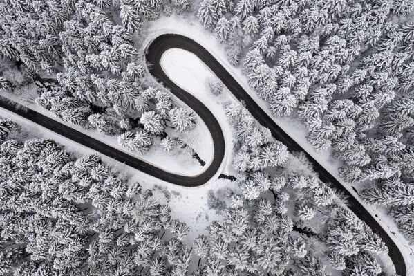 На этой фотографии, сделанной 9 декабря 2021 года, показан вид с высоты птичьего полета на дорогу в снежную погоду в Ксонрупт-Лонгемере, восточная Франция. - Sputnik Латвия