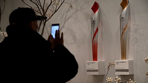 Мужчина фотографирует факелы Зимних Олимпийских и Паралимпийских игр в Пекине в 2022 - Sputnik Латвия