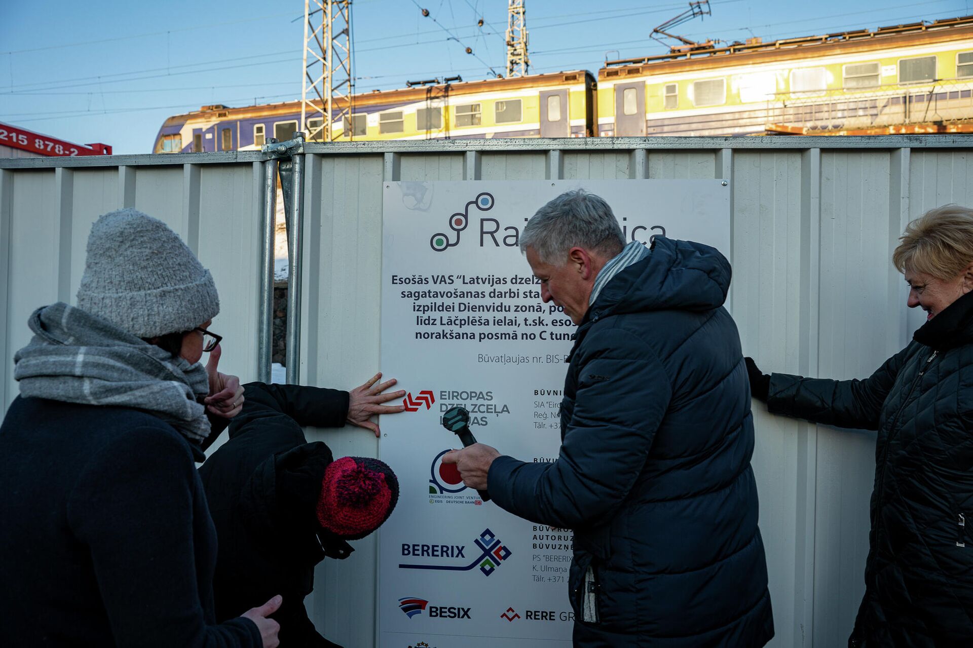 Участники мероприятия устанавливают информационный щит на заборе строительной площадки - Sputnik Латвия, 1920, 13.01.2022
