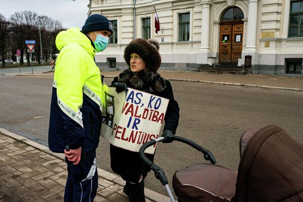 Полицейский останавливает женщину с плакатом. - Sputnik Латвия