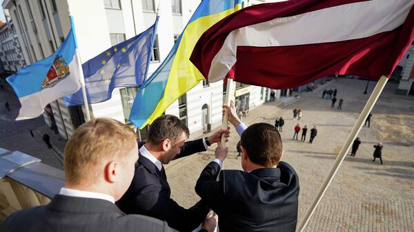 Мэр Риги Мартиньш Стакис и посол Украины в Латвии Александр Мищенко водрузили флаг Украины на здании Рижской думы в знак поддержки  - Sputnik Латвия