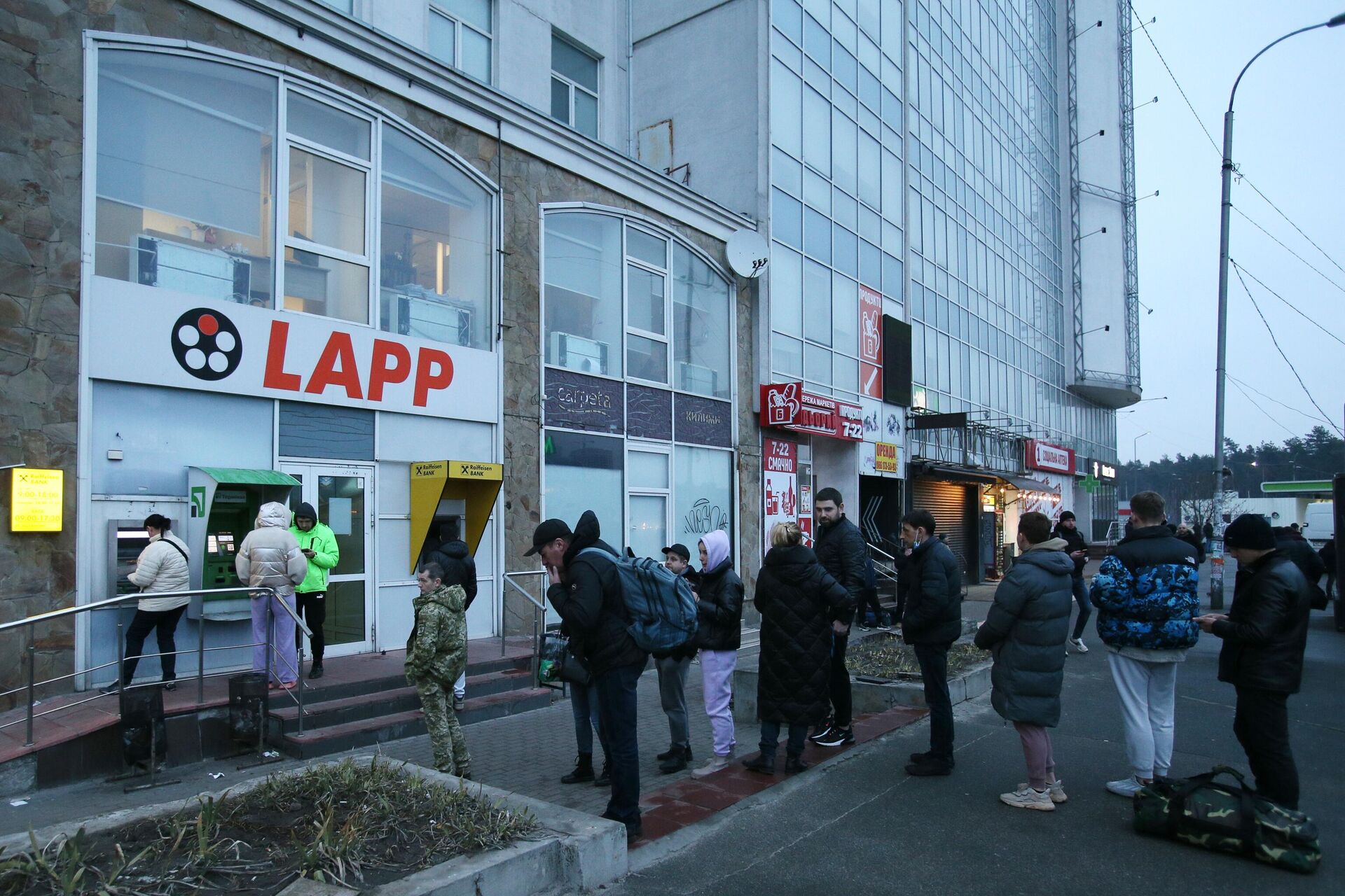 Люди стоят в очереди для того чтобы снять денежные средства в банкомате на одной из улиц в Киеве Люди стоят в очереди для того чтобы снять денежные средства в банкомате на одной из улиц в Киеве - Sputnik Латвия, 1920, 24.02.2022