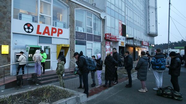 Люди стоят в очереди для того чтобы снять денежные средства в банкомате на одной из улиц в Киеве - Sputnik Латвия