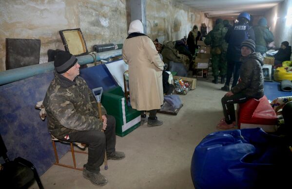 Nikolajevkas ciemata iedzīvotāji, DTR aizsargi un žurnālisti paslēpjas ēkas pagrabā. - Sputnik Latvija