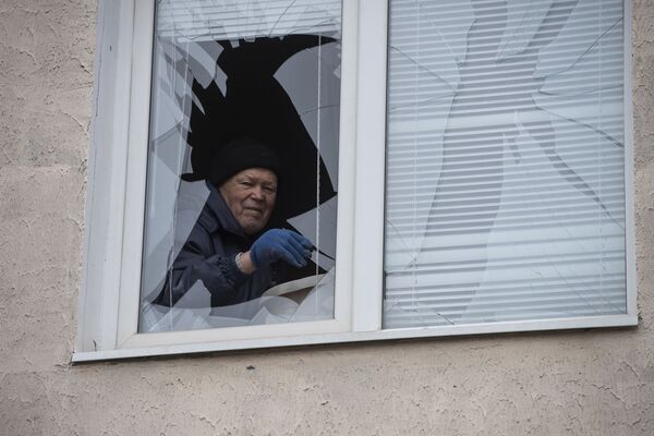 Мужчина достает осколки из разбитого окна в жилом доме в городе Счастье в Луганской народной республике - Sputnik Латвия