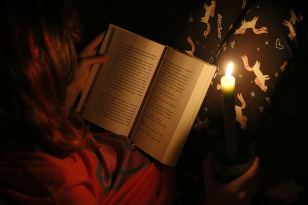 Bērns lasa grāmatu sveču gaismā – Kijevā notika elektrības atslēgšanas tests - Sputnik Latvija