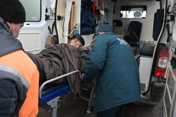 Сотрудники МЧС переносят пожилого человека, добравшегося из Мариуполя до пункта приема беженцев в санитарную машину. - Sputnik Латвия