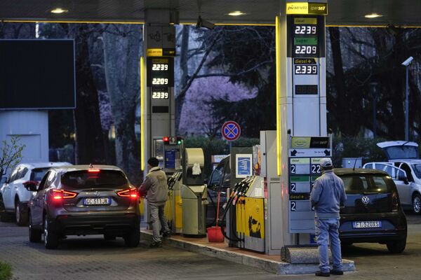 Работник меняет цены на топливо на табло на заправочной станции в Милане. - Sputnik Latvija
