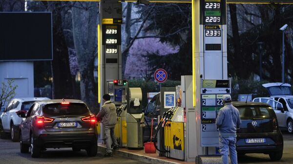 Работник меняет цены на топливо на табло на заправочной станции в Милане - Sputnik Latvija