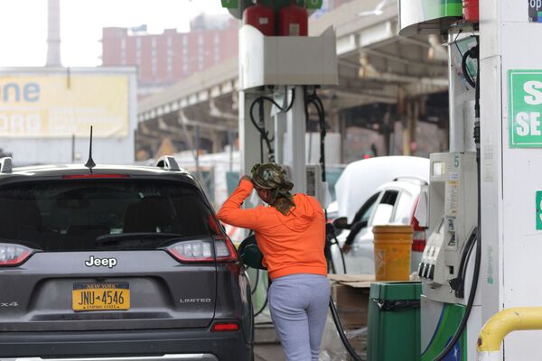 Женщина заправляет автомобиль на заправочной станции в Манхэттене, штат Нью-Йорк. - Sputnik Latvija