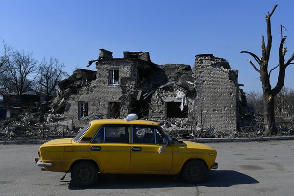 Автомобиль проезжает мимо разрушенного дома в Волновахе - Sputnik Латвия