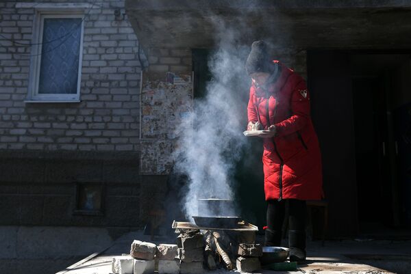 Женщина готовит еду на костре во дворе жилого дома в Волновахе - Sputnik Латвия