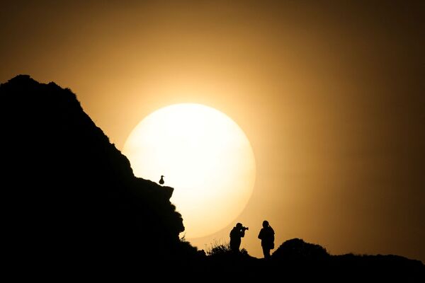 Пара фотографируется во время заката на вершине Порт д&#x27;Аваль, знаменитой арки скал Этрета на западе Франции. - Sputnik Латвия