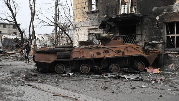 Уничтоженный бронетранспортер БТР-82 у разрушенного жилого дома в Мариуполе - Sputnik Латвия