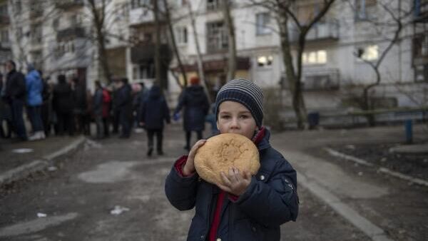 Bērns ar maizi rokas, kamēr motokluba Nakts vilki nodaļa Donbass izdala humanitāro palīdzību Rubežnoje pilsētā. Tā nomalēs vēl turpinājās kaujas, nav gaismas un ūdens. Cilvēki tiek evakuēti apšaudēs. Pilsēta ir uz humanitārās katastrofas robežas   - Sputnik Latvija