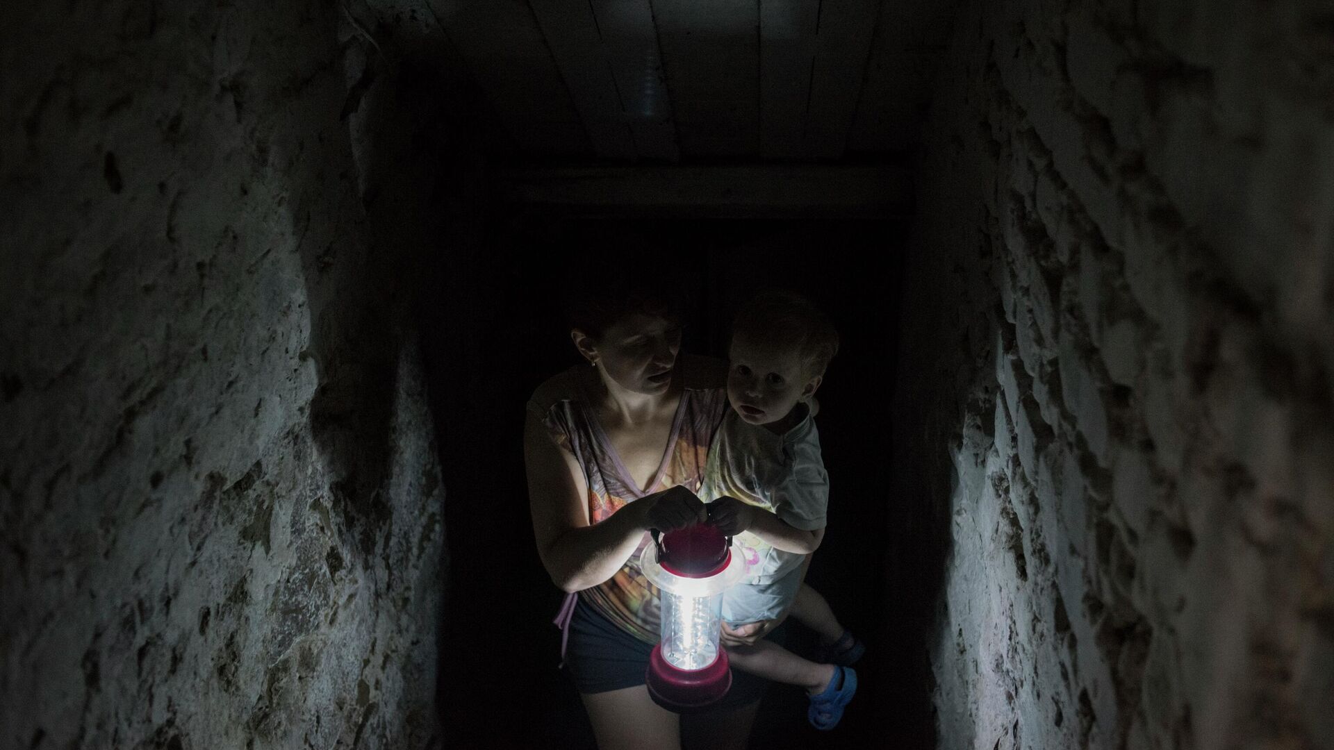 Женщина с ребенком прячется в подвале своего дома в Горловке, 30 июня 2016 года  - Sputnik Латвия, 1920, 16.09.2023