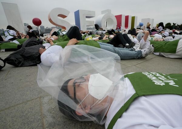 Активист с полиэтиленовым пакетом на голове лежит на земле во время перформанса, посвященного Дню Земли против изменения климата в Сеуле - Sputnik Латвия