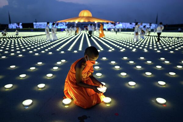 Молодой буддийский монах устанавливает светодиодный светильник в рамках празднования &quot;Дня Земли&quot; в буддийском храме Ват Дхаммакая в провинции Патхумтхани - Sputnik Латвия