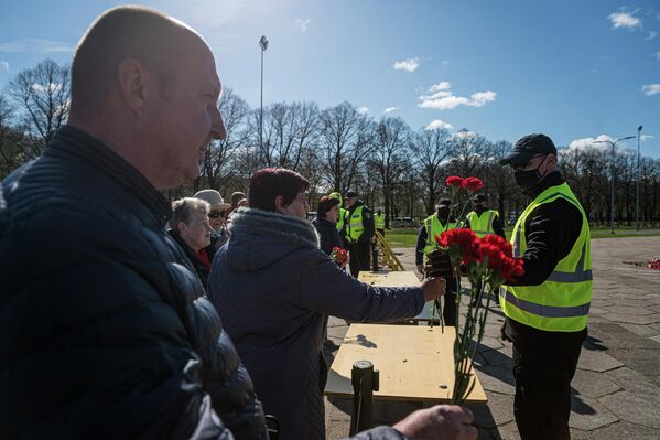 Волонтеры принимают цветы у жителей Риги, которые пришли почтить память советским войнам, погибшим за освобождение от немецко-фашистского захватчика. - Sputnik Латвия