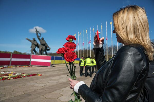 Девушка фотографирует на память красные гвоздики на фоне памятника Освободителям Риги. - Sputnik Латвия