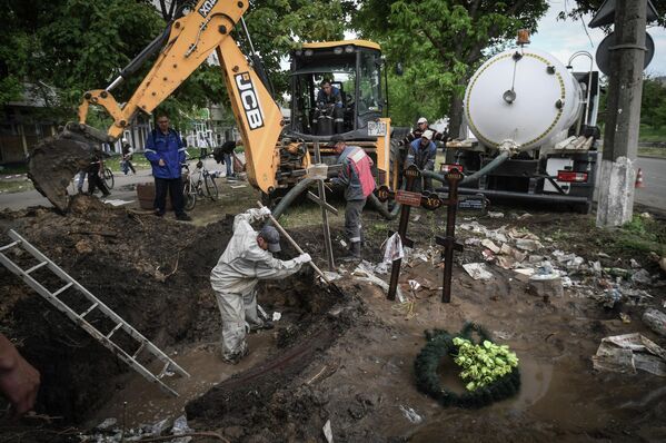 Проводится эксгумация тел местных жителей, захороненных на улице в Мариуполе, из-за прорыва водопровода в месте захоронения. - Sputnik Латвия