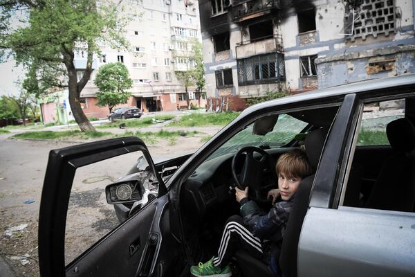 Дети играют в разбитой машине возле одного из домов в Мариуполе - Sputnik Латвия