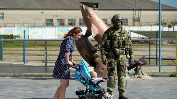 Sieviete ar bērnu ratiņiem Hersonas krastmalā līdzās Krievijas karavīriem  - Sputnik Latvija