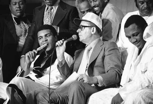 Мухаммед Али ест мороженое, а Джо Фрейзер улыбается, когда официальный представитель бокса Мэдисон-Сквер-Гарден Джон Кондон (в центре) проводит пресс-конференцию после боя после победы Али 28 января 1974 года в Нью-Йорке единогласным решением судей. - Sputnik Латвия