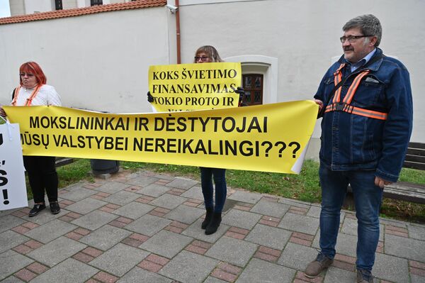 Участники акции протеста держат плакат с надписью: &quot;Ученые и преподаватели нашему государству не нужны?&quot;. - Sputnik Латвия