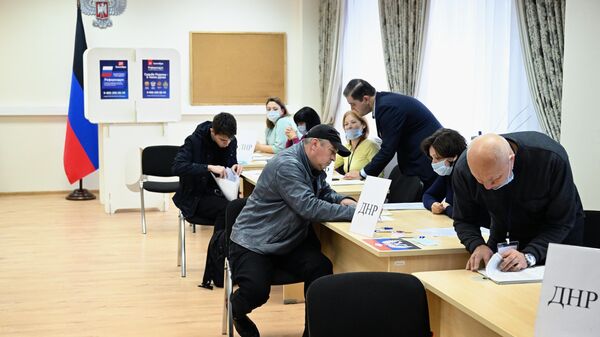 Мужчины голосуют на референдуме о присоединении Донецкой народной республики и Луганской народной республики к России на избирательном участке в посольстве ДНР в Москве - Sputnik Латвия