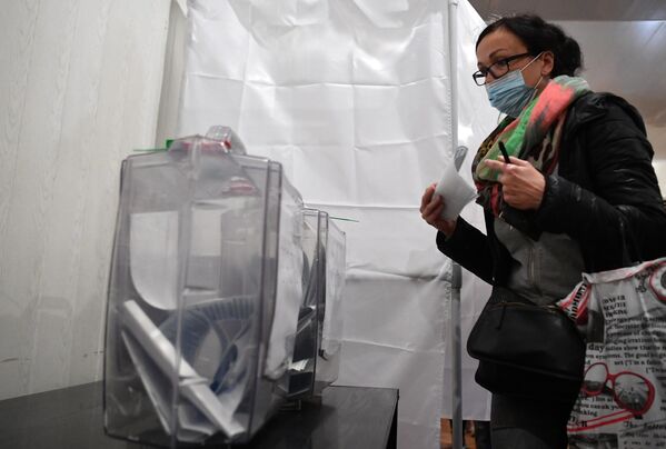 Женщина голосует на референдуме о присоединении Запорожской области к России на избирательном участке на мелитопольском предприятии. - Sputnik Латвия