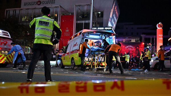 Сеульские спасатели помогают пострадавшим и вывозят погибших с улицы, где во время празднования Хэллоуина из-за давки остановилось сердце у десятков людей, Южная Корея - Sputnik Латвия
