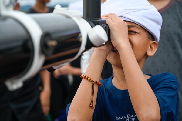 Учащийся исламской школы-интерната смотрит в телескоп, готовясь наблюдать за лунным затмением в Индонезии. - Sputnik Латвия