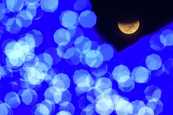 Фаза лунного затмения на площади в Каракасе, Венесуэла. Здесь его наблюдали ранним утром во вторник. - Sputnik Латвия
