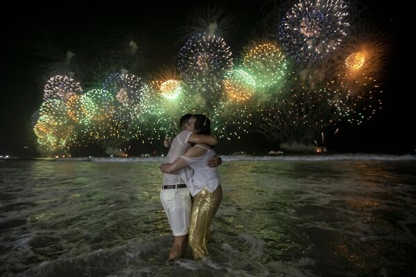 Люди празднуют начало Нового года на фоне фейерверков над пляжем Копакабана в Рио-де-Жанейро, Бразилия, рано утром в воскресенье, 1 января 2023 года. - Sputnik Латвия
