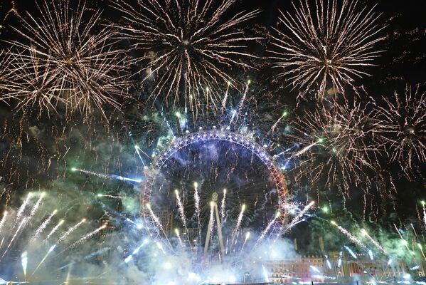 Фейерверки освещают небо над колесом обозрения Лондонский глаз в центре Лондона в воскресенье, 1 января 2023 года - Sputnik Латвия