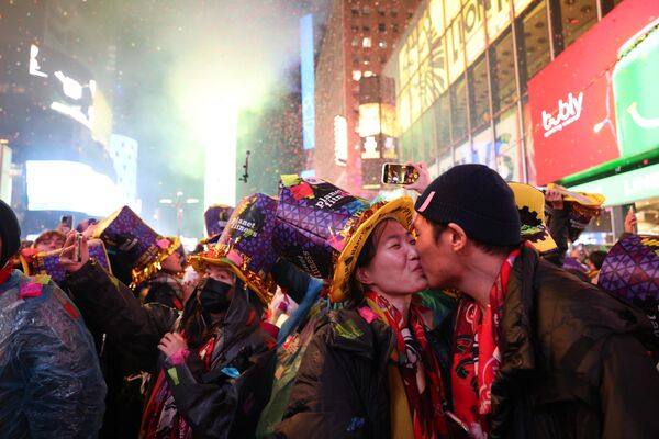 Люди целуются, когда начинает падать конфетти, чтобы отметить начало нового года, на Таймс-сквер, Нью-Йорк, 1 января 2023 года. - Sputnik Латвия