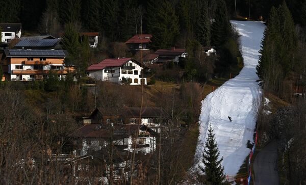 Лыжник скатывается по искусственному снежному склону в Оберстдорфе, южная Германия, 27 декабря 2022 года при температуре около шести градусов тепла. - Sputnik Латвия