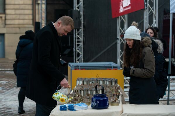 Спикер Сейма Латвии Эдвардс Смилтенс с помощью чайника отливает окопные свечи для армии Украины. - Sputnik Латвия