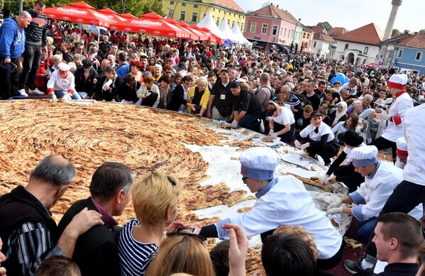 Боснийские повара и их ученики разрезают самый большой в мире пирог с мясным фаршем, известный как &quot;борек&quot;, на центральной площади острова Тузла. Он весил 650 кг и имел диаметр 6,5 м. Для его изготовления потребовалось 1,5 км вручную раскатанного теста. - Sputnik Латвия