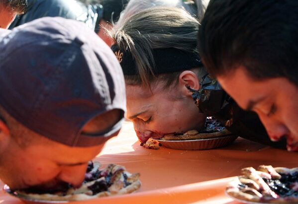 Люди участвуют в конкурсе по поеданию пирогов в Лос-Анджелесе. Победитель должен первым съесть пирог без помощи рук. - Sputnik Латвия