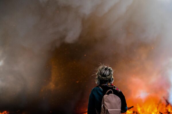 Девушка во время сожжения арт-объекта Четвертая стена в виде 19-метрового куба на праздновании Масленицы в арт-парке Никола-Ленивец Калужской области - Sputnik Латвия